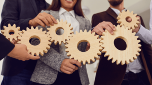 Employees holding a wooden made gears and putting it together