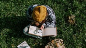 girl holding magnifying glass and looking through a notebook