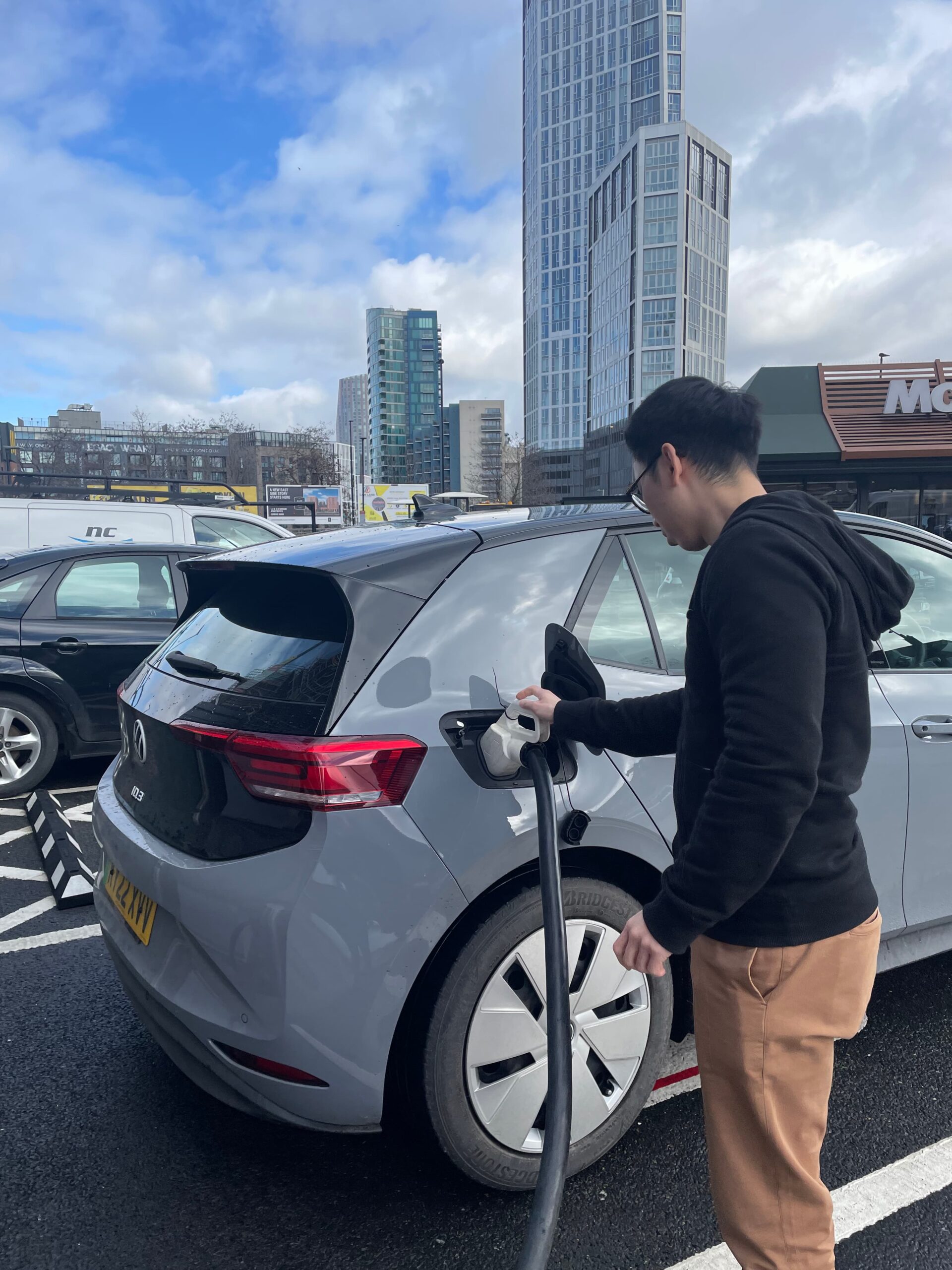 Elvin looks at the car whilst connecting the charger cable